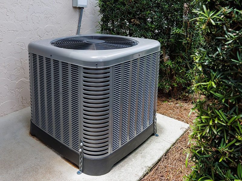 Modern HVAC air conditioner unit on concrete slab outside of hou